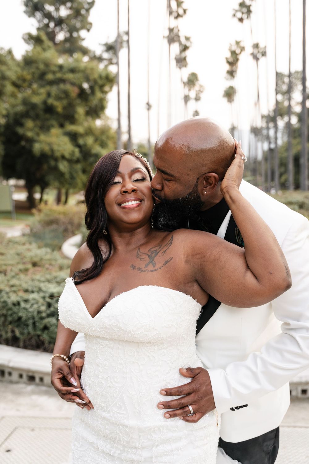 A loving couple shares an intimate moment during an outdoor wedding photoshoot, with the bride wearing a stunning white dress.
