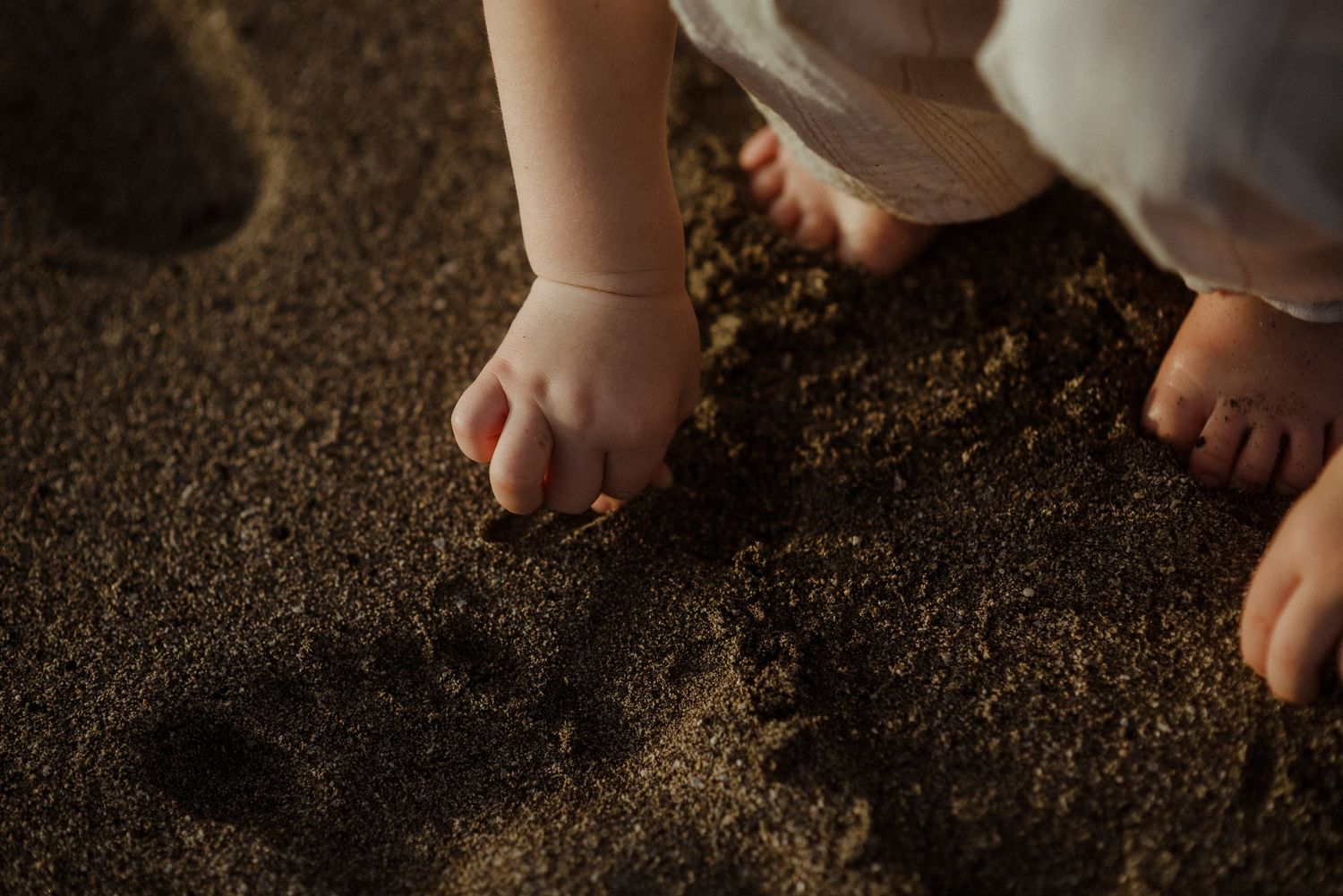 Small bare feet standing on dark sandy beach. Tenerife Wedding Photographer at Playa del Duque, Adeje.