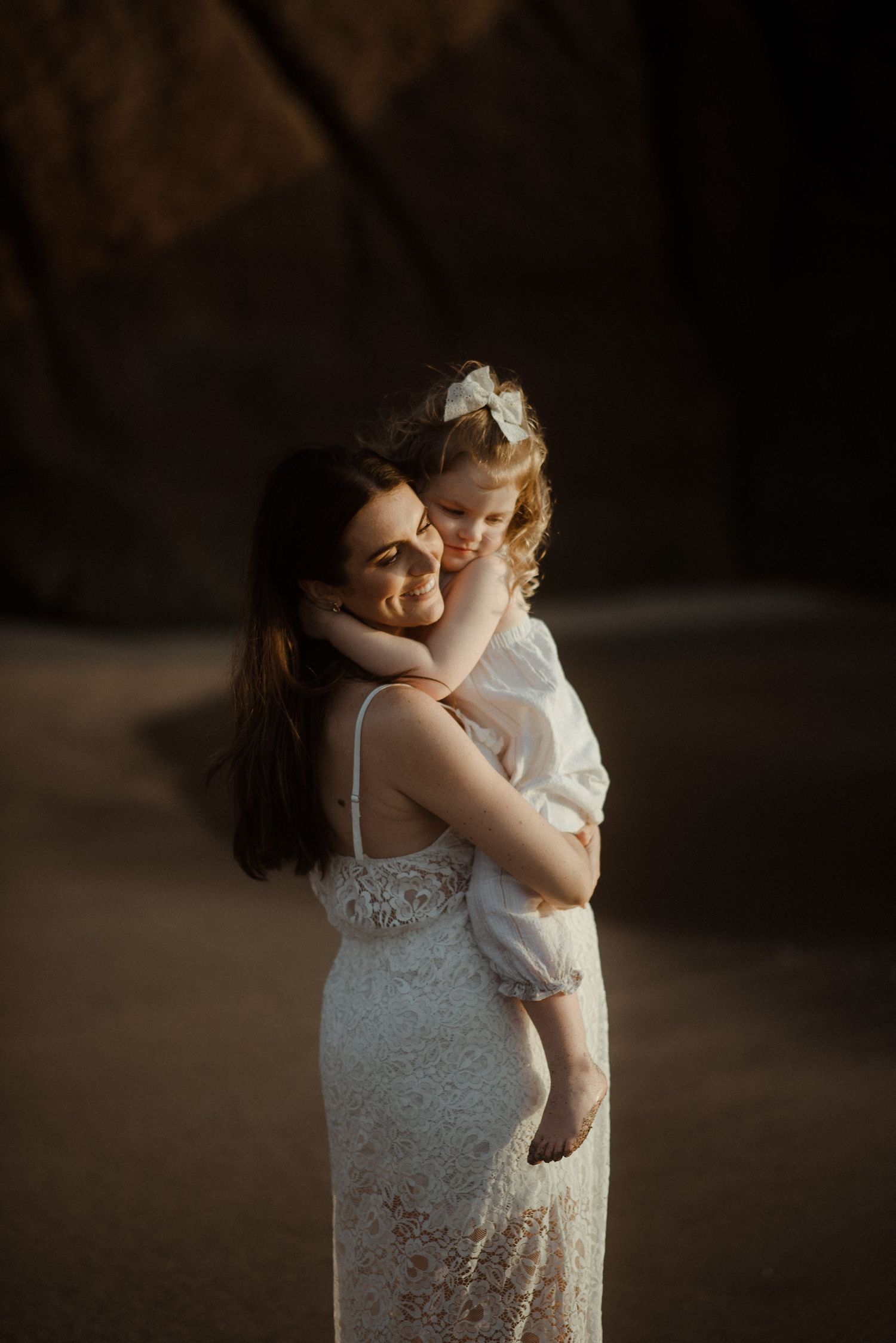Intimate moment captured between parent and child on beach near rocky cliffs. Tenerife Wedding Photographer at Playa del Duque, Adeje.