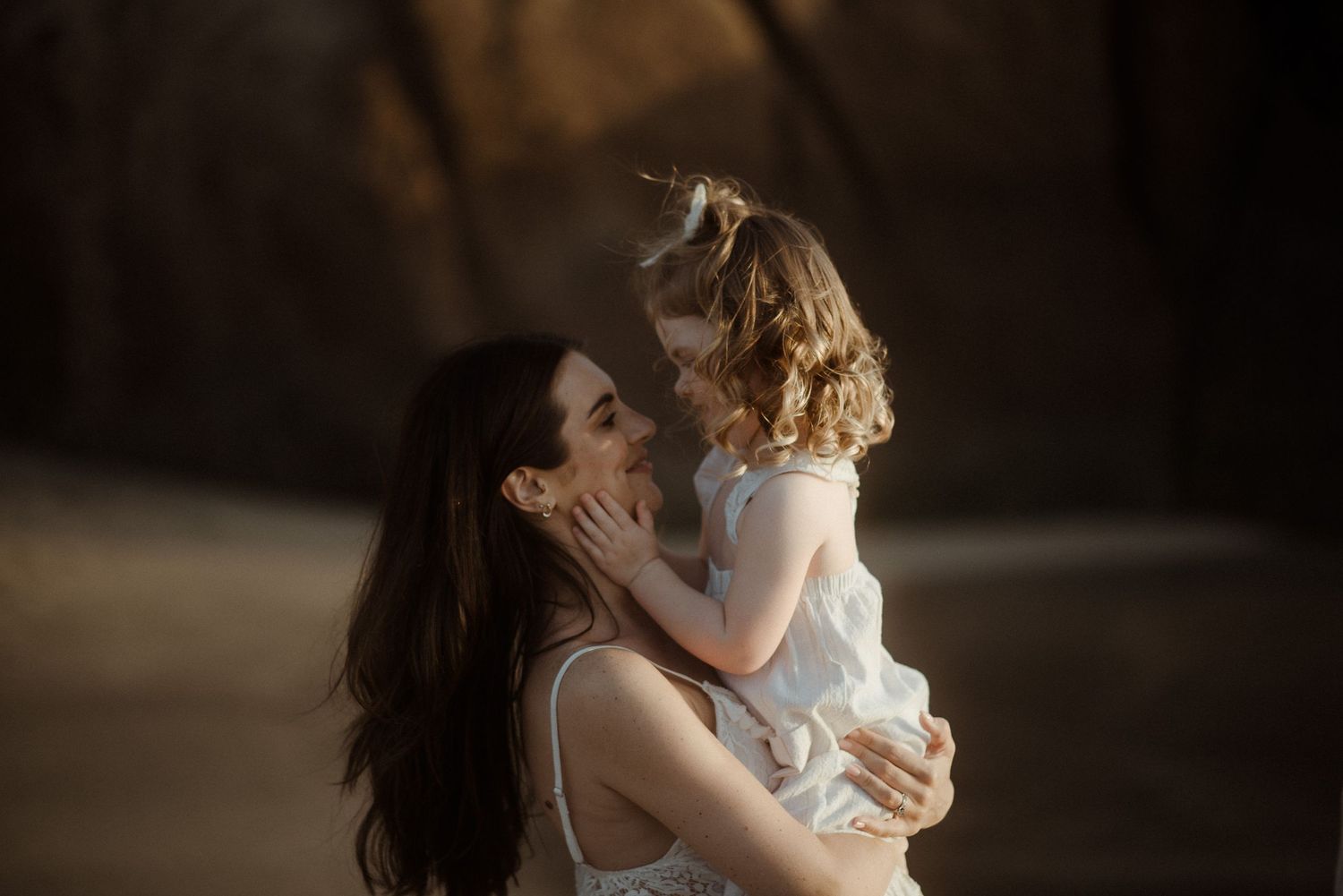 Tender moment between parent and child against dramatic beach backdrop. Tenerife Wedding Photographer at Playa del Duque, Adeje.