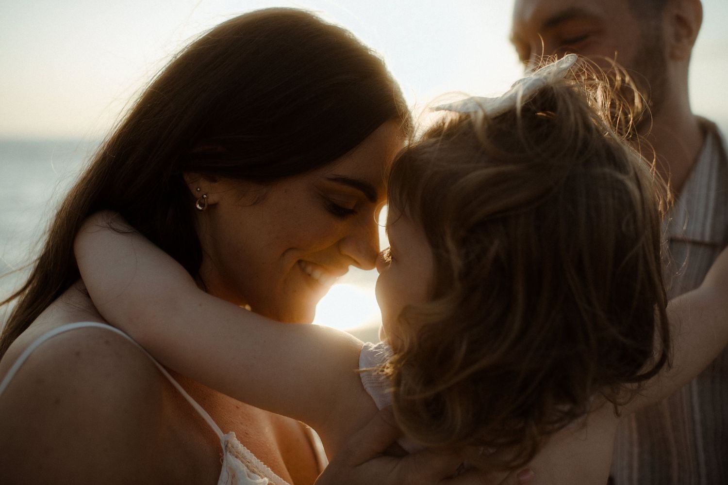 Intimate family moment captured in golden sunlight on beach. Tenerife Wedding Photographer at Playa del Duque, Adeje.