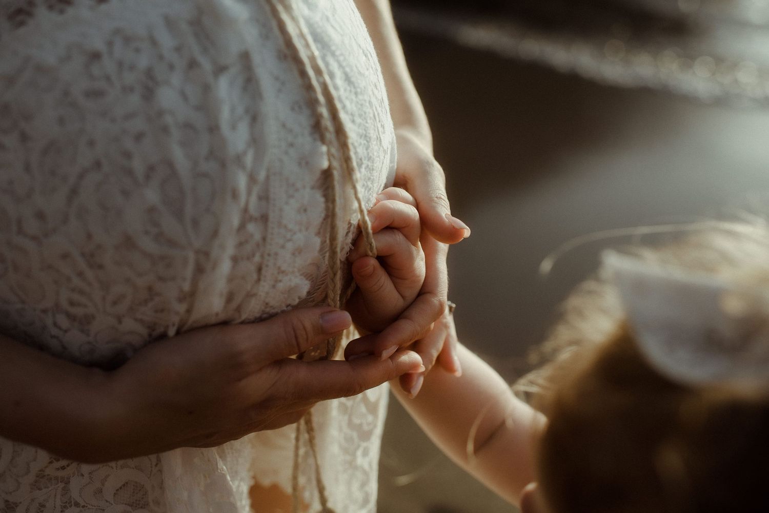 Close-up view of hands touching a white lace dress fabric. Tenerife Wedding Photographer at Playa del Duque, Adeje.