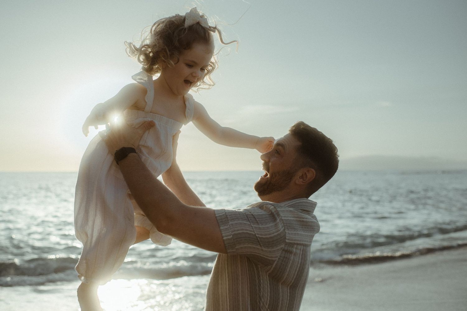 Joyful beachside moment with white dress against sparkling ocean backdrop. Tenerife Wedding Photographer at Playa del Duque, Adeje.