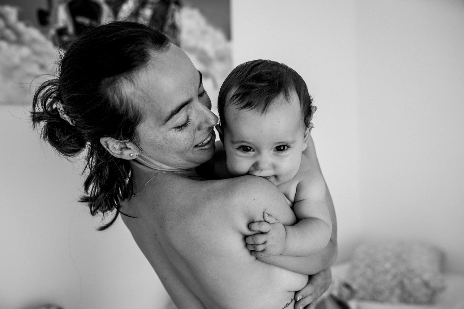 A tender black and white photo of parent and baby sharing an intimate moment together.