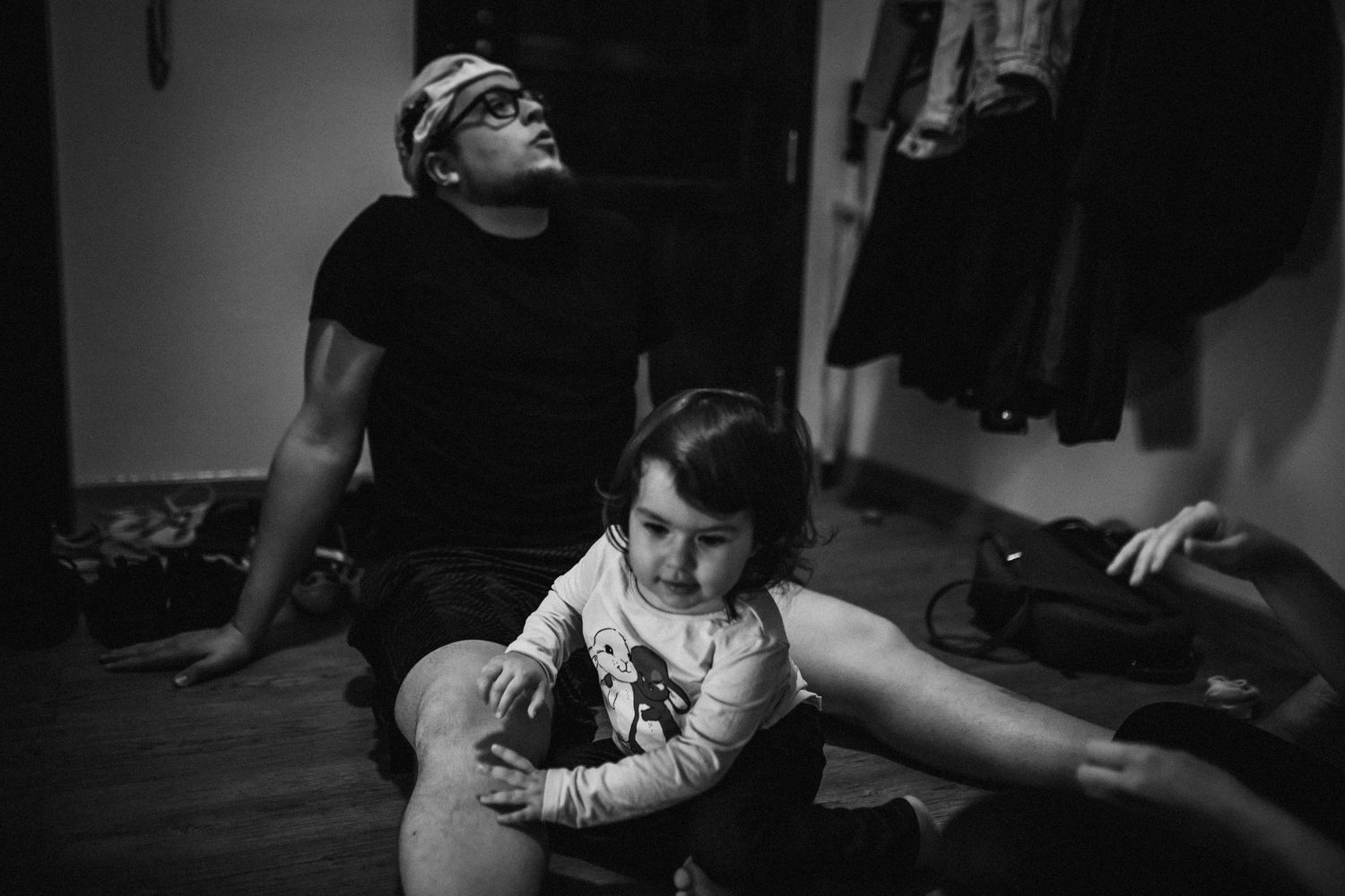 A black and white intimate portrait of two people sitting together on a wooden floor.