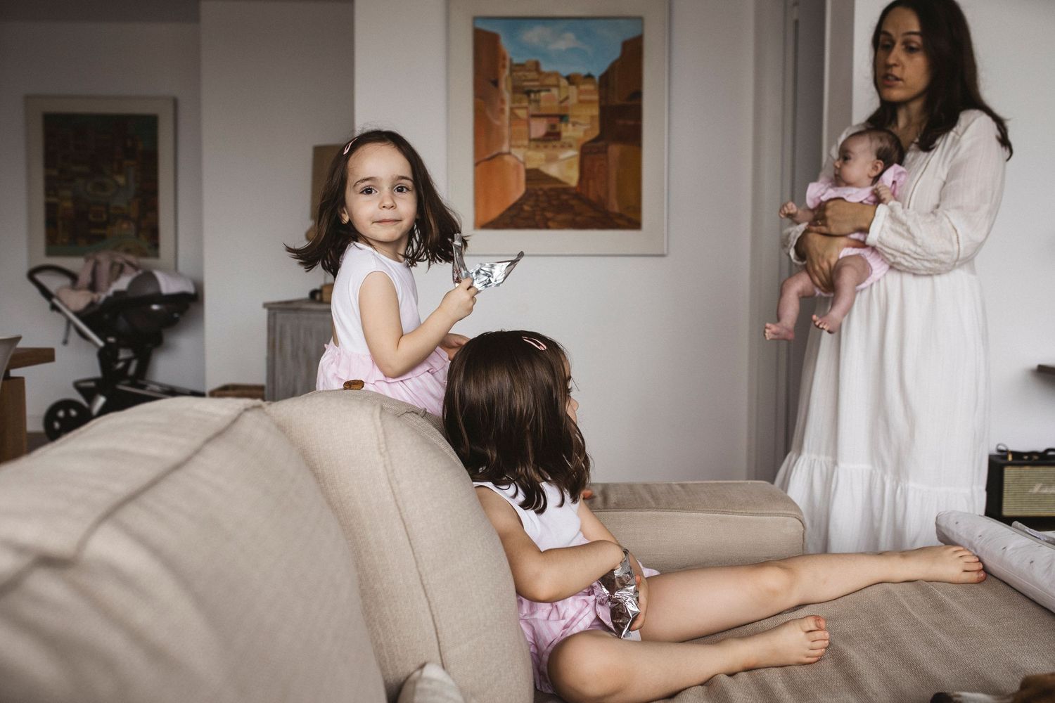 A casual family moment in a living room with a beige couch and framed artwork on the wall.