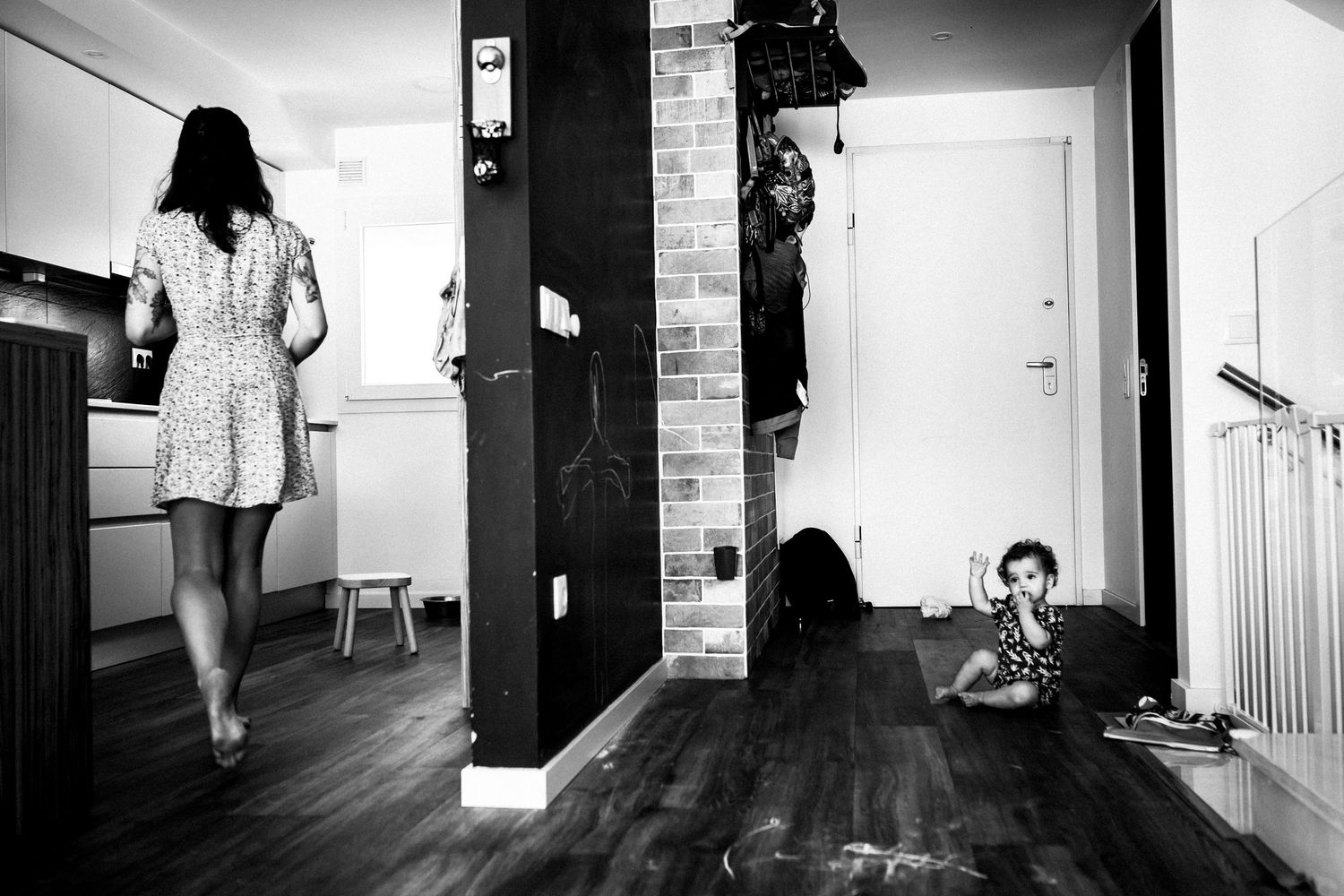 Black and white interior scene showing contrasting parallel views of a modern living space divided by a large pillar.