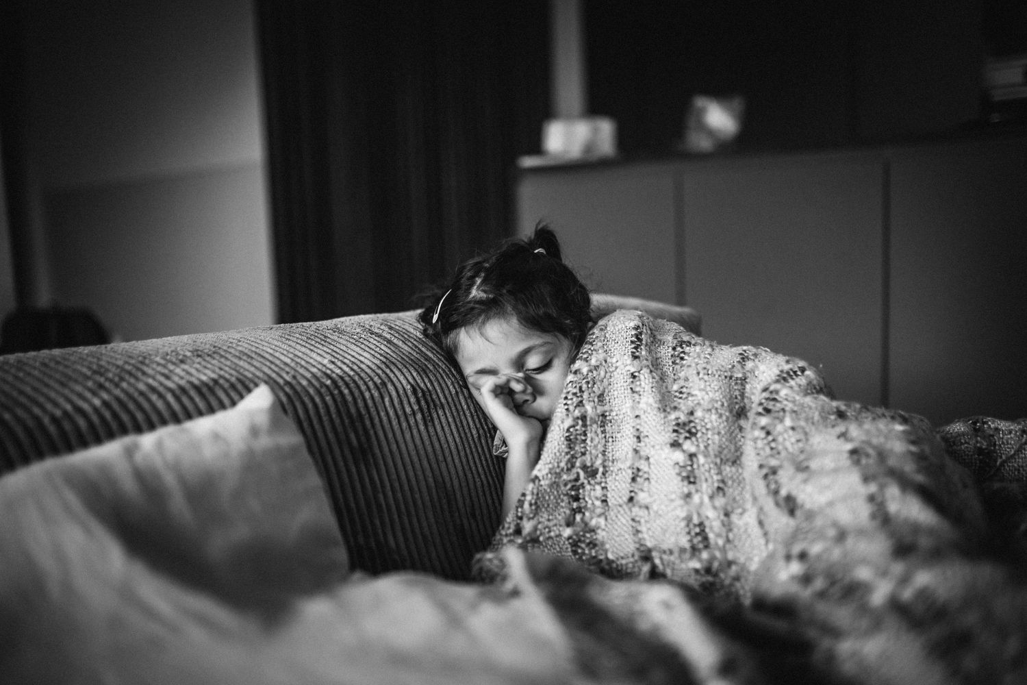 A sleeping figure rests peacefully under cozy floral bedding in a black and white photograph.
