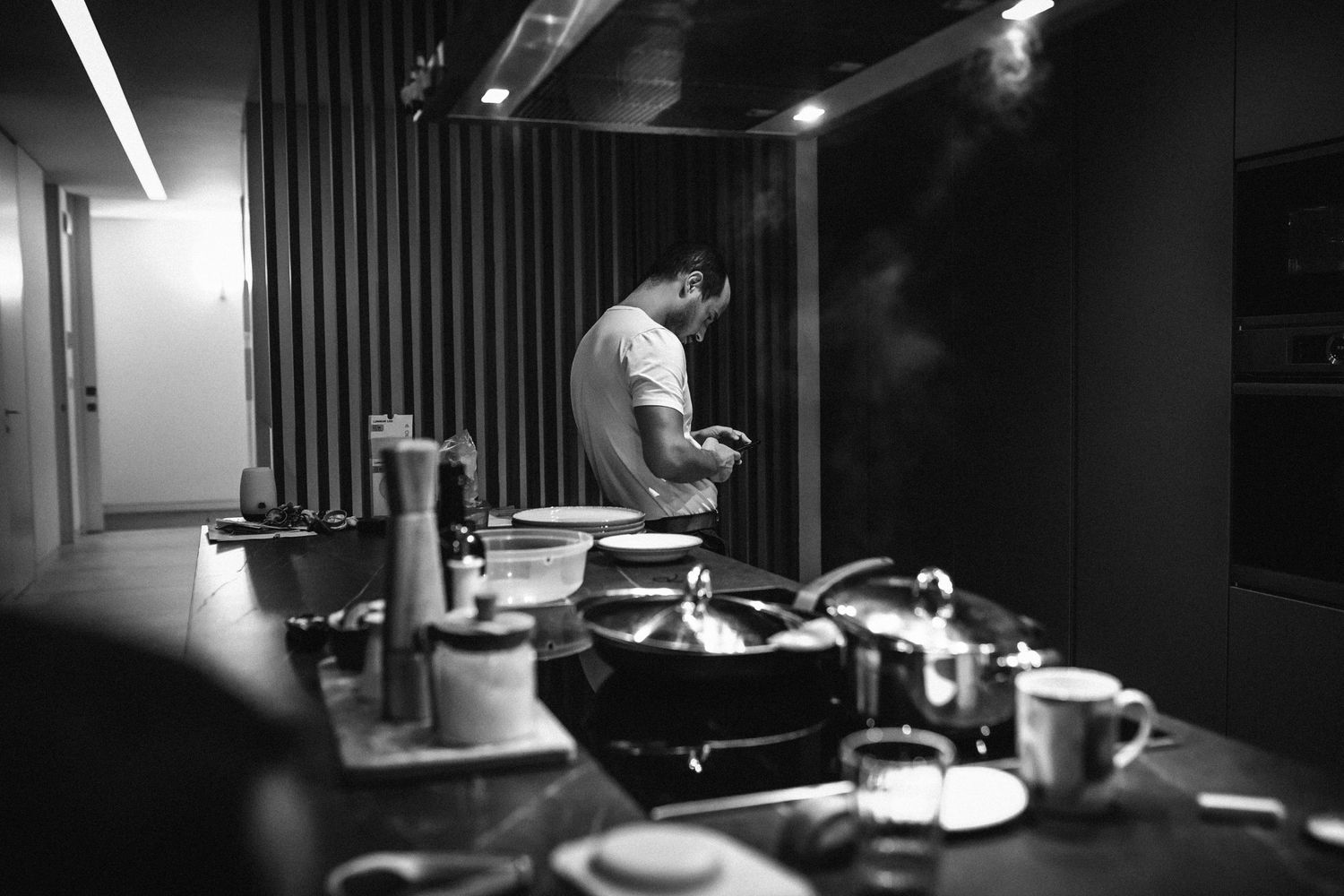 Black and white photo of someone working in a dimly lit recording studio with mixing equipment and instruments.