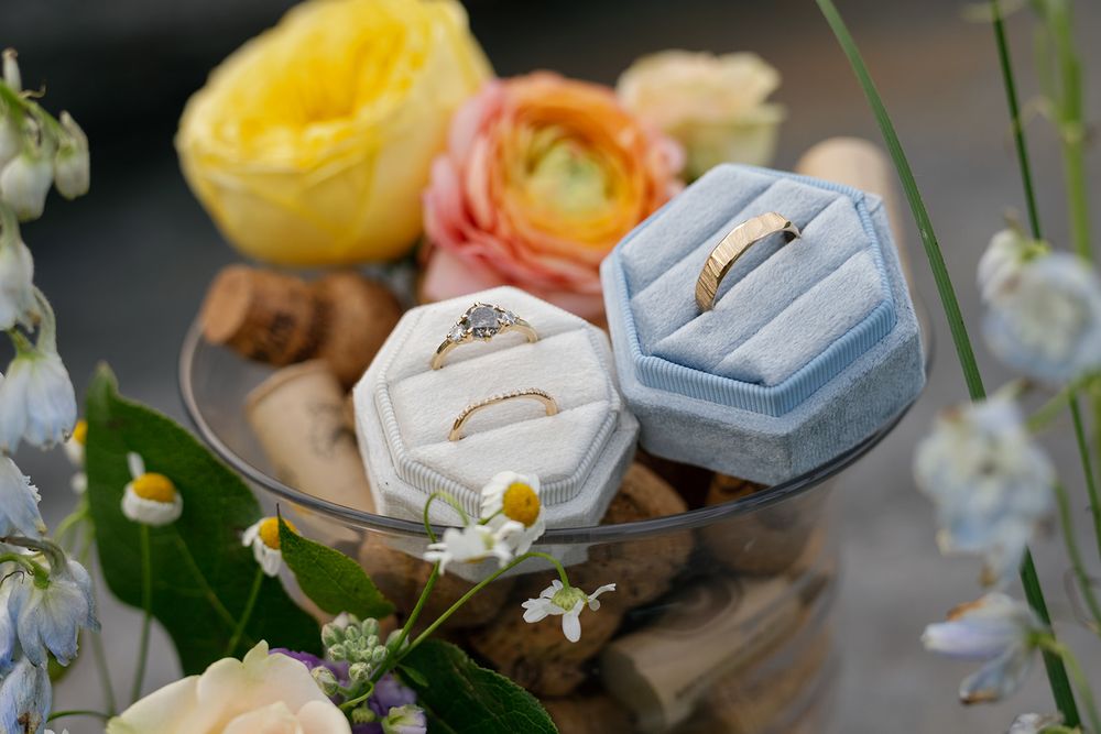 A delicate dessert table displays fresh pastries, yellow flowers, and white ornate plates in an elegant garden party setting.