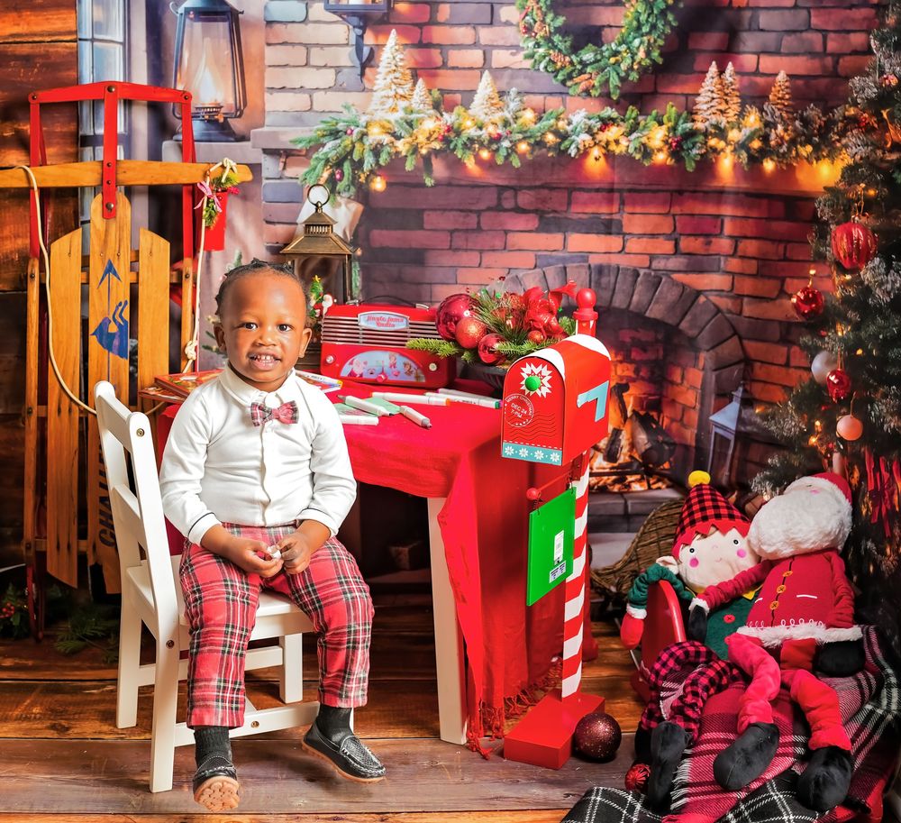 A festive Christmas setting with plaid decor, red toys, and a rustic brick backdrop adorned with holiday greenery.