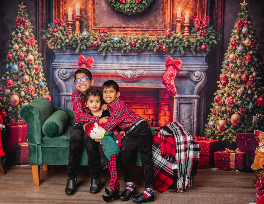 Festive Christmas scene with red and green decor featuring decorated trees, fireplace, stockings and cozy armchair.