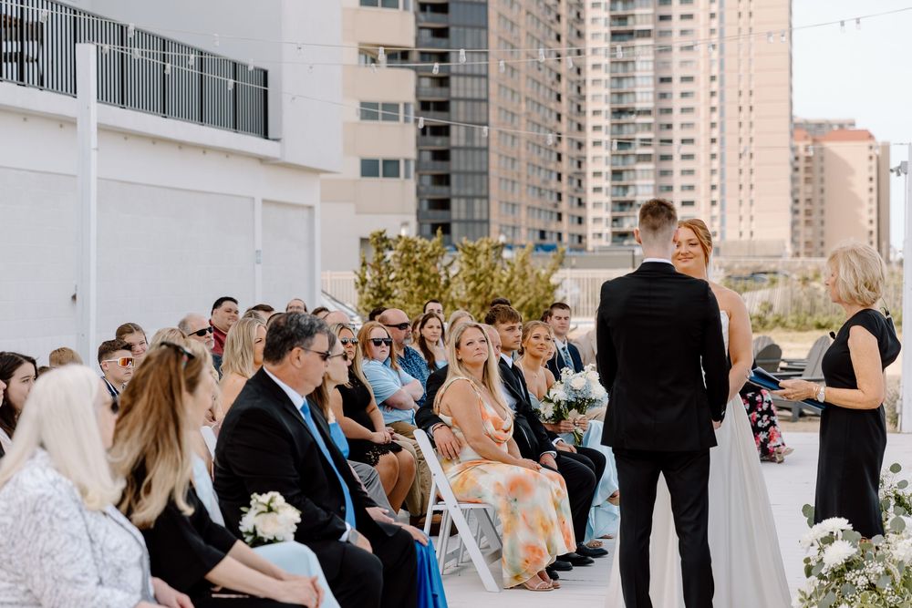 A rooftop wedding ceremony in progress with guests seated in rows and a couple standing before an officiant in the city.