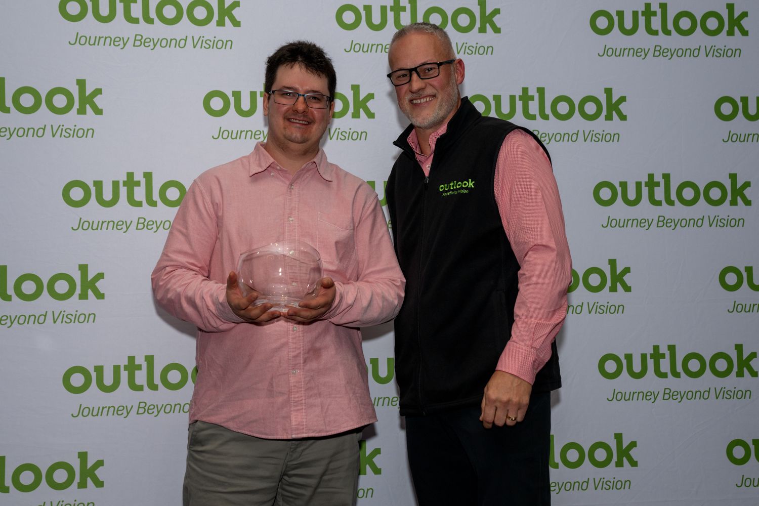 Two people posing with award in front of green Outlook Nebraska backdrop.