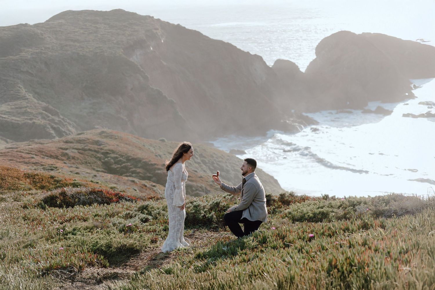 A proposal scene on a dramatic coastal cliff overlooking the ocean.