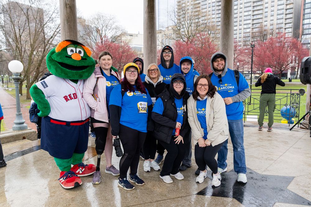 A group poses with the Boston Red Sox mascot Wally the Green Monster at an outdoor event during autumn.