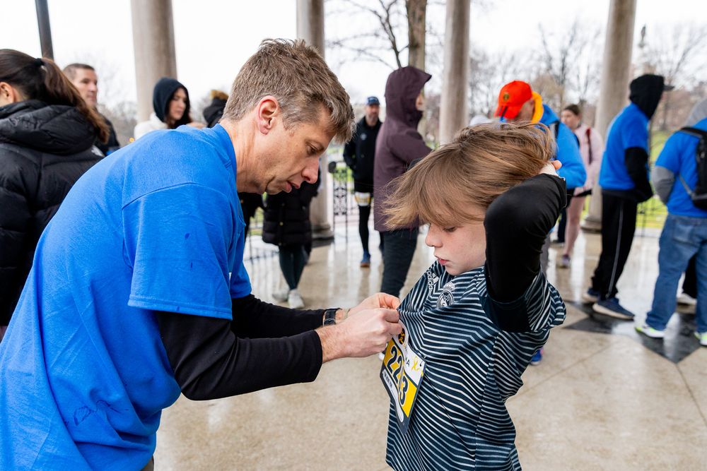 A person in a blue shirt signs an autograph for a young fan at an outdoor event.