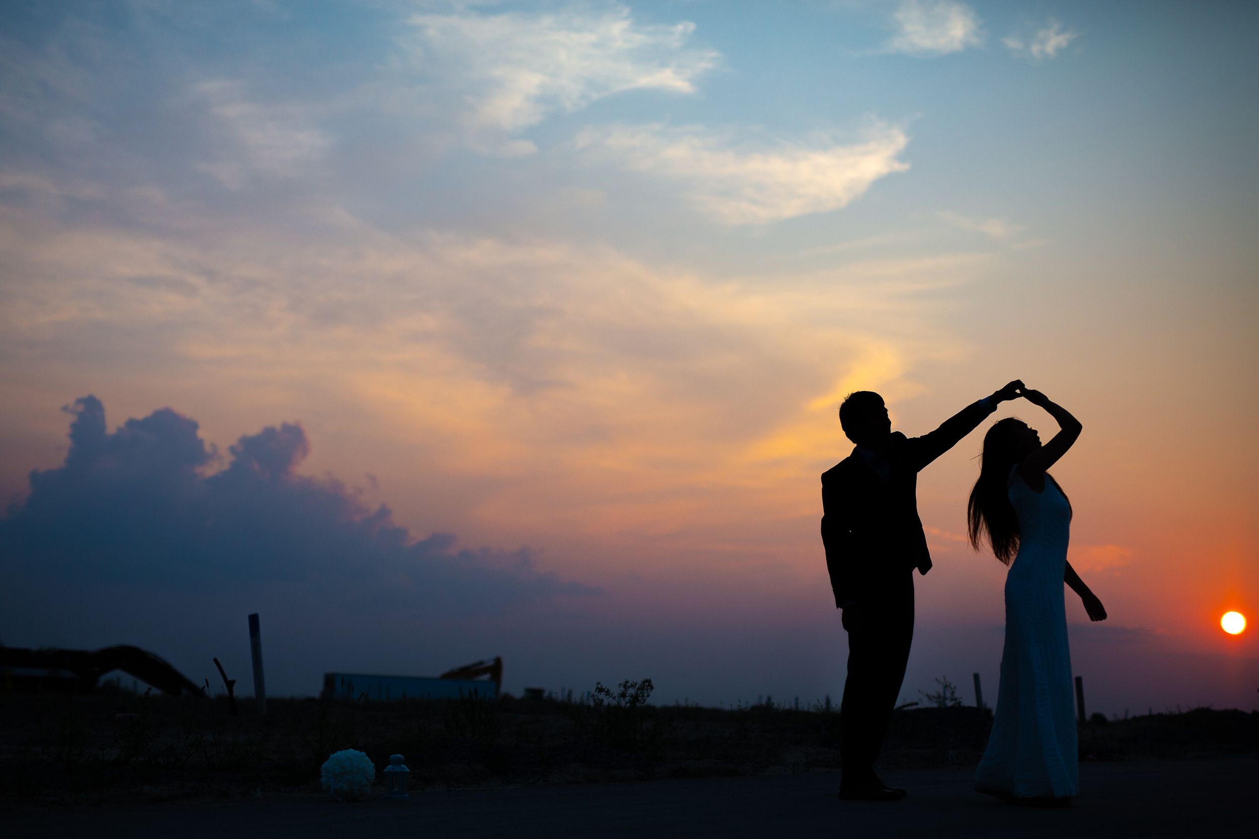 Couple dancing in silhouette against vibrant sunset sky.