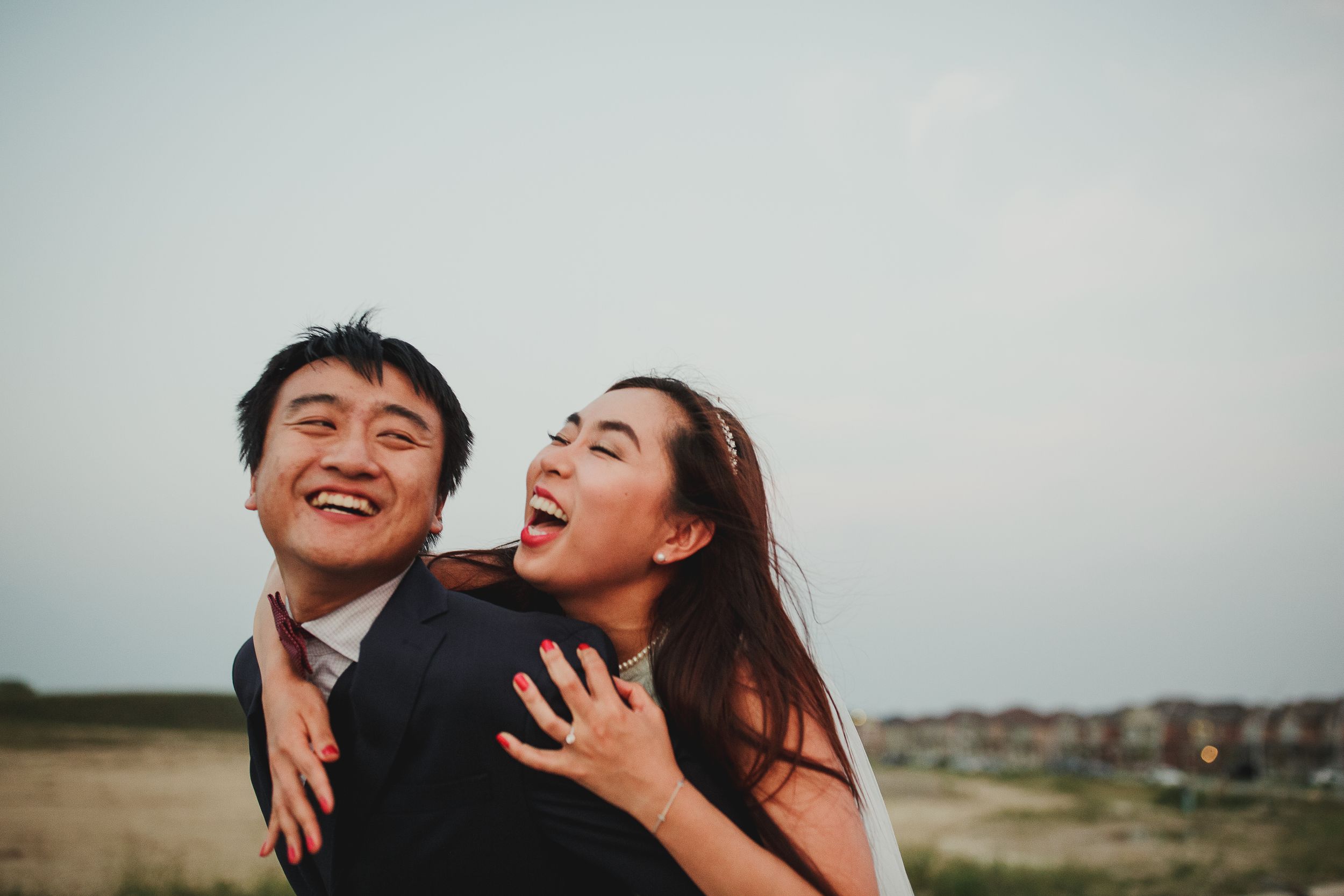Joyful couple sharing a candid laughing moment during their wedding photoshoot.