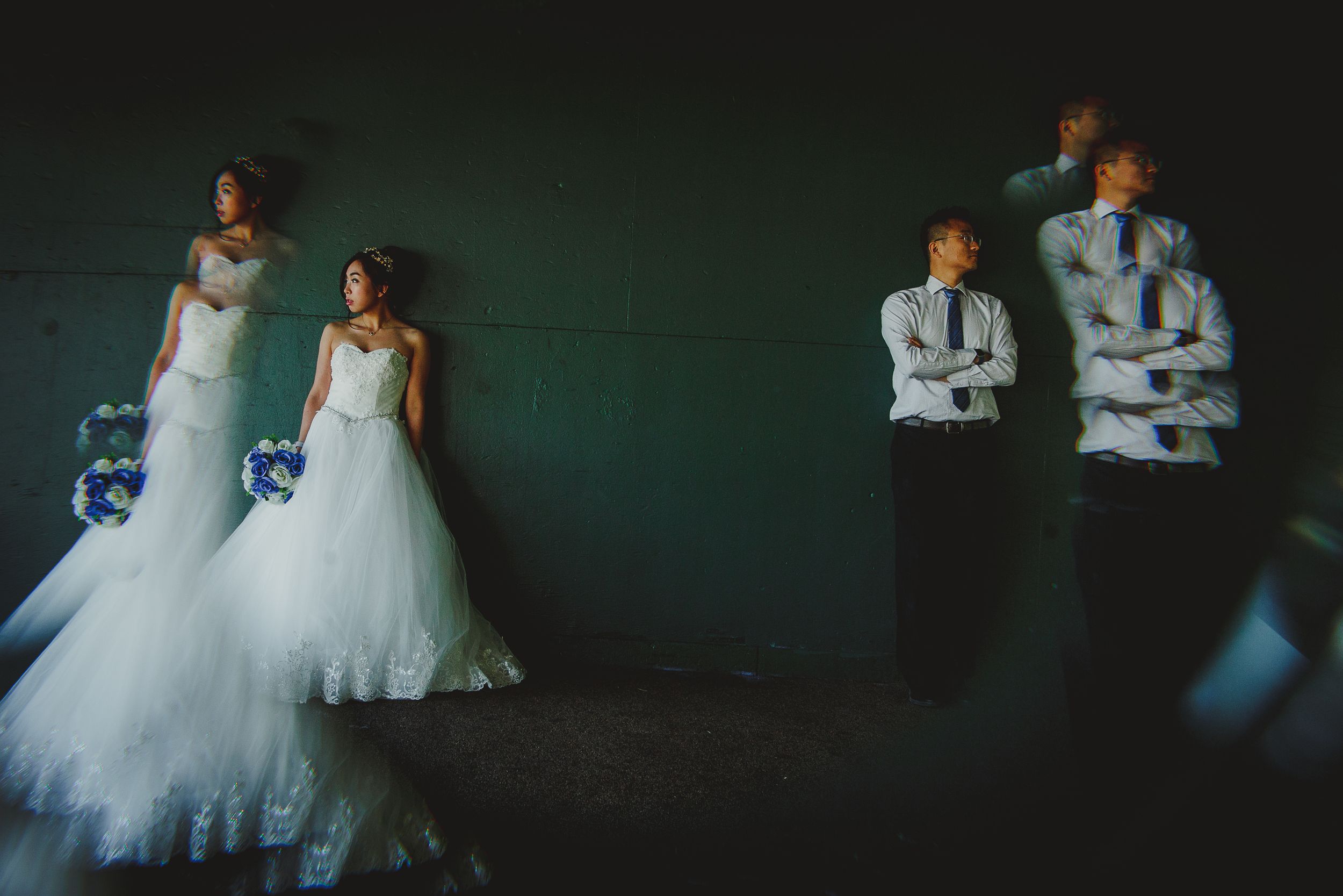 Wedding party poses dramatically against a green wall in an artistic composition.