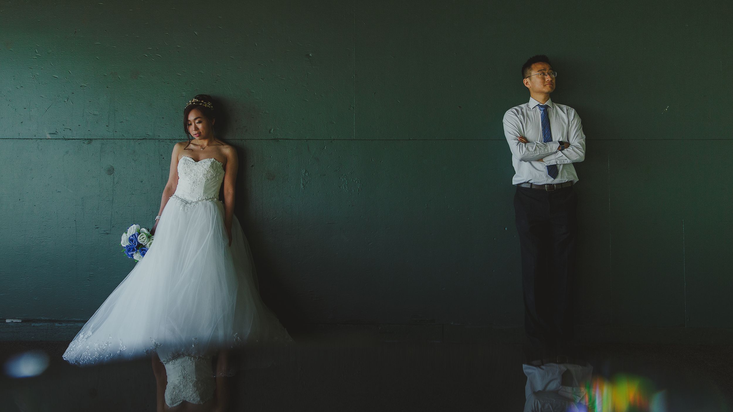 Stylized wedding portrait with couple positioned apart against a green backdrop.