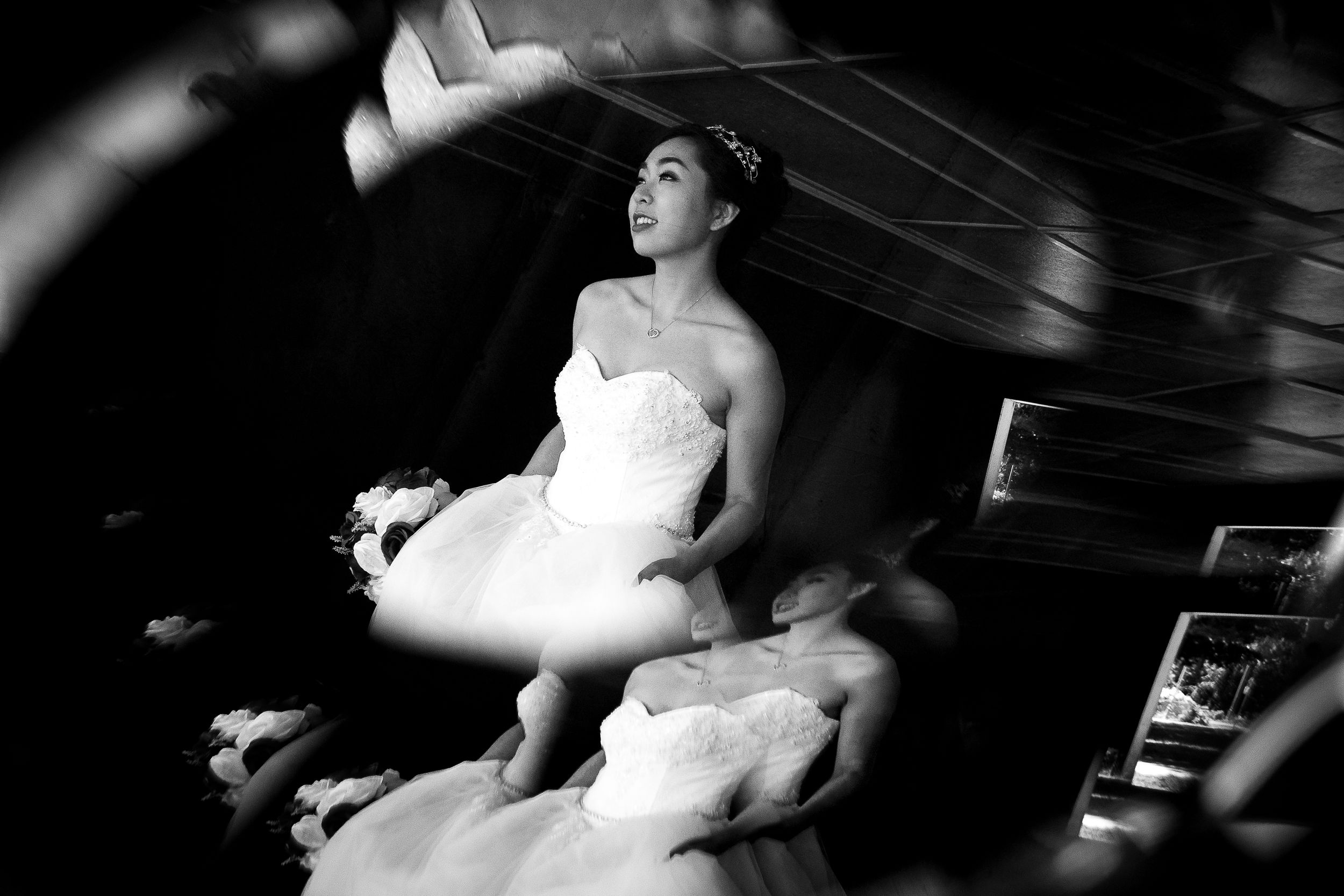 Black and white photo of bride in wedding dress getting ready with dramatic lighting and movement.