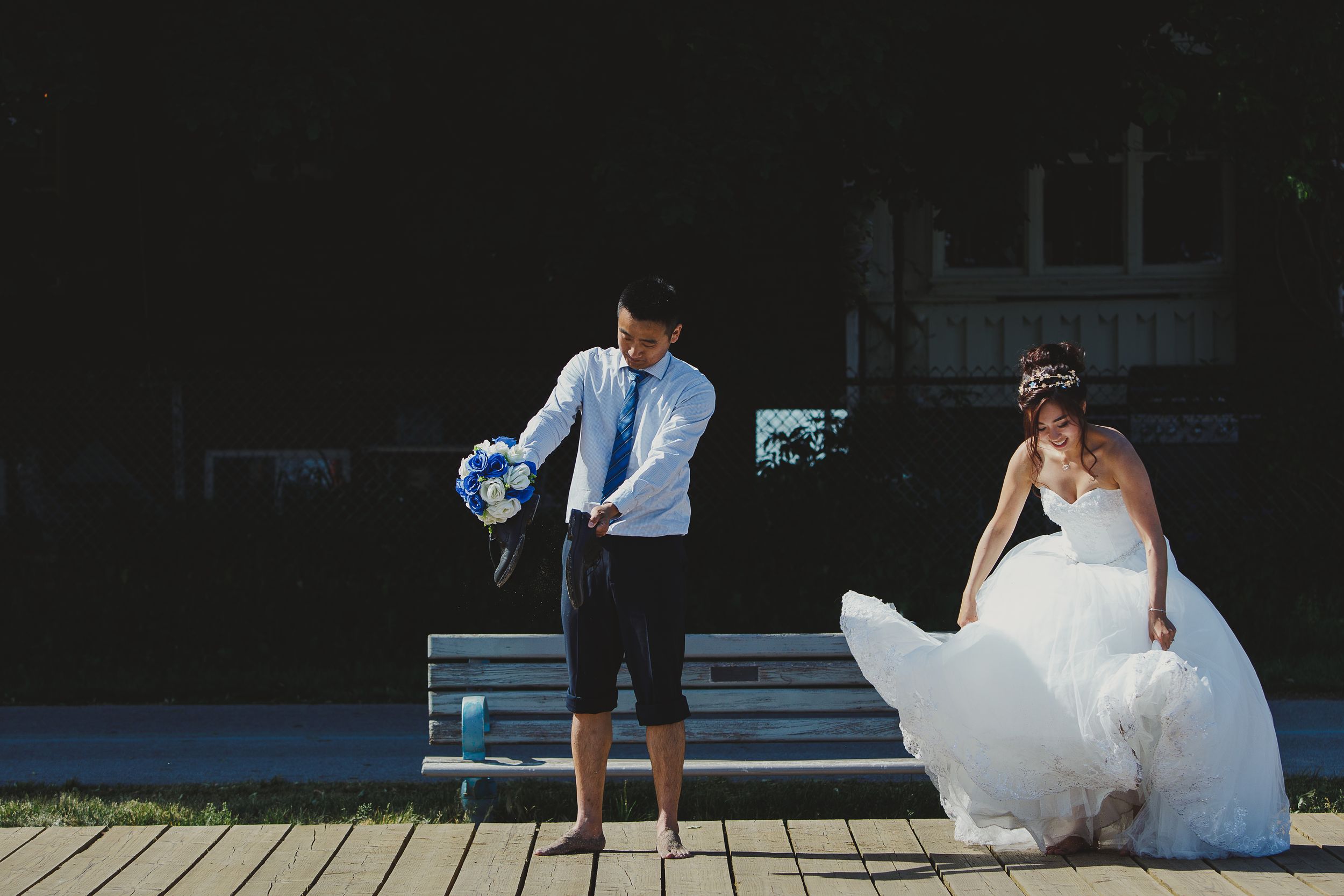 Candid wedding photo on wooden deck with bride's dress flowing in wind.