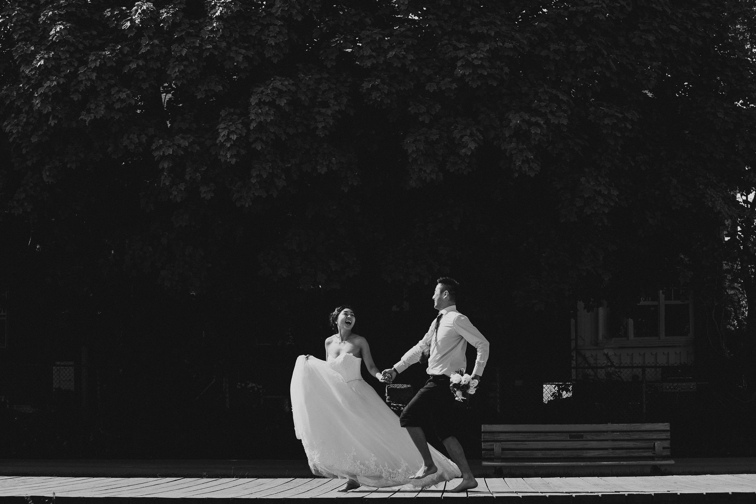 A couple dancing playfully in black and white with the bride's dress twirling.