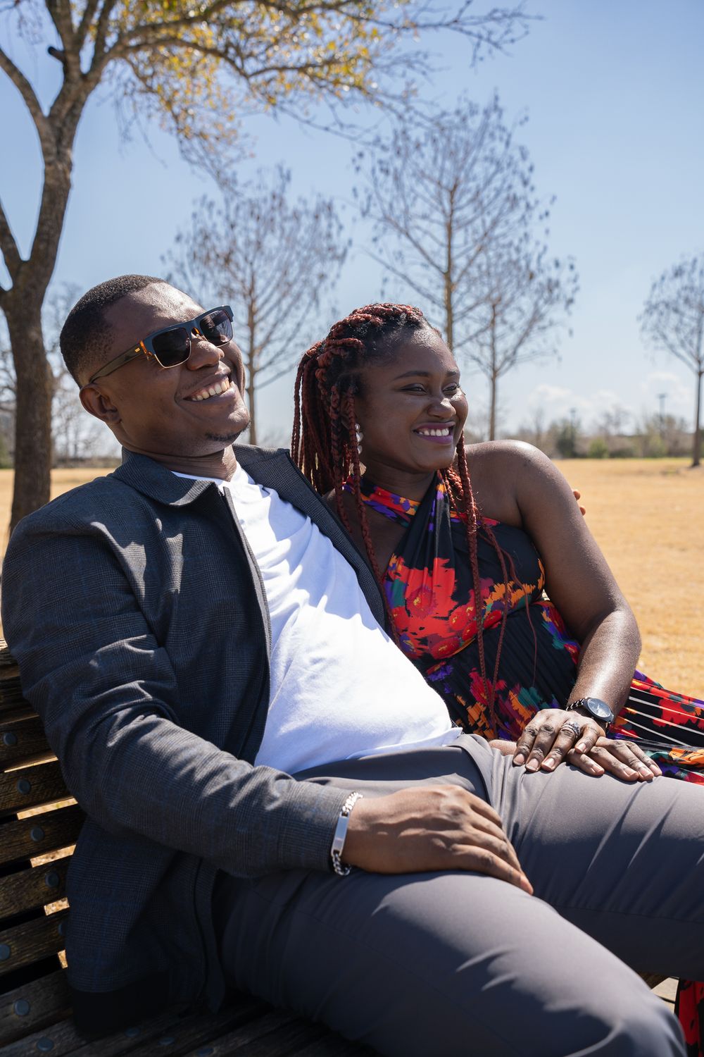 A couple shares a joyful moment while relaxing on a bench outdoors.