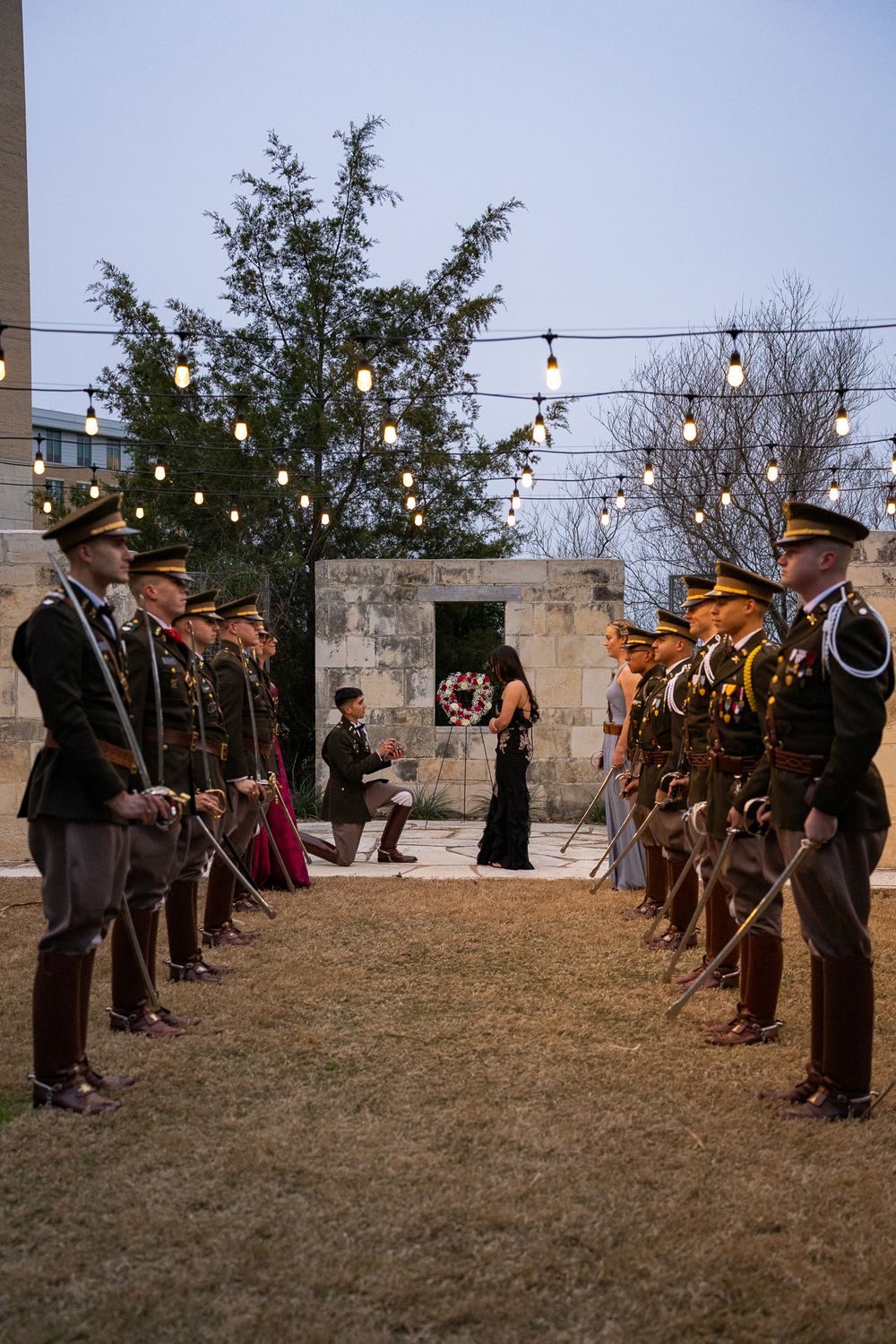 Honor guard forming a walkway with raised swords at an outdoor evening ceremony.