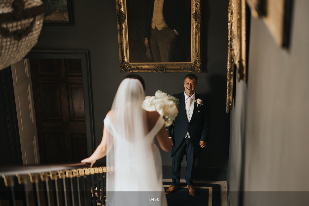 A bride and groom share a candid moment on an elegant staircase in a dimly lit historic venue.
