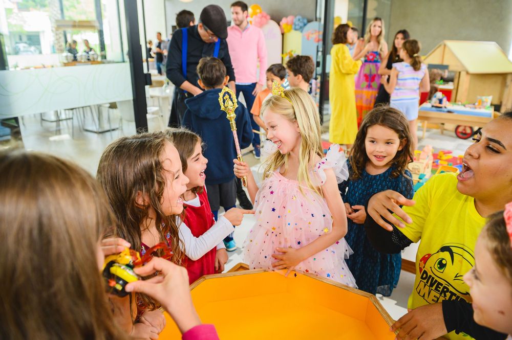 A group of people wearing colorful party attire gather around a table at a festive social event.