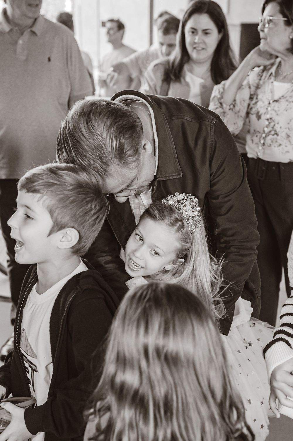 A black and white candid photo showing people sharing a joyful moment at a social gathering.
