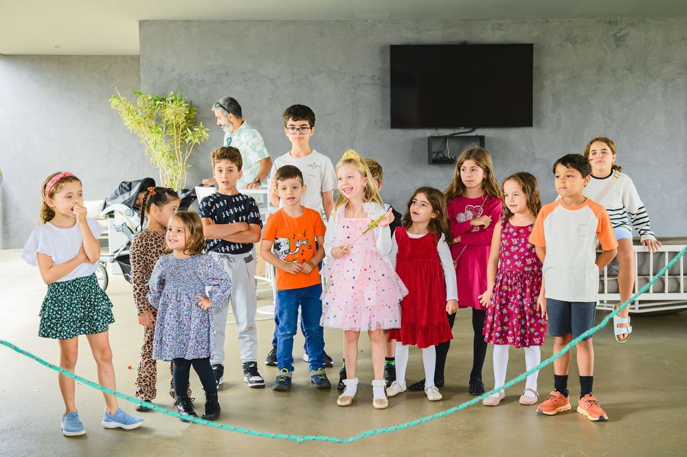 Young children stand in line and play together during outdoor activities at a preschool gathering area.