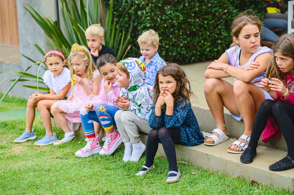 Group of children sitting together on garden steps looking at mobile devices and tablets.