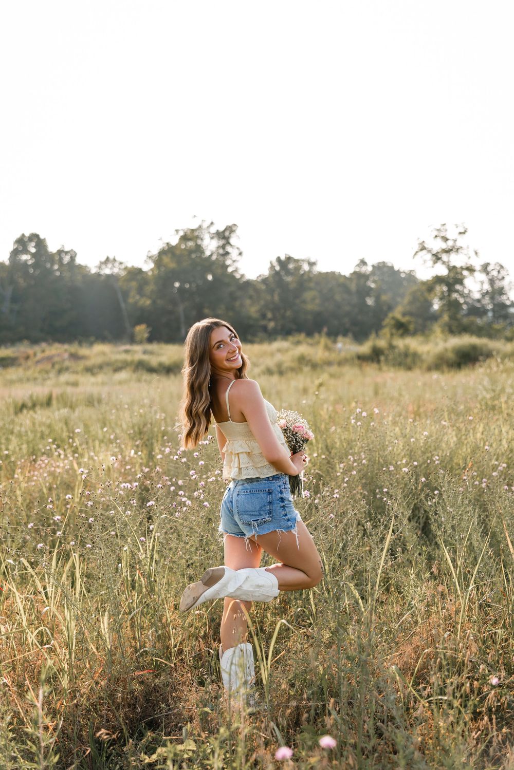 A person in denim shorts frolics joyfully through a sunlit wildflower meadow at golden hour.