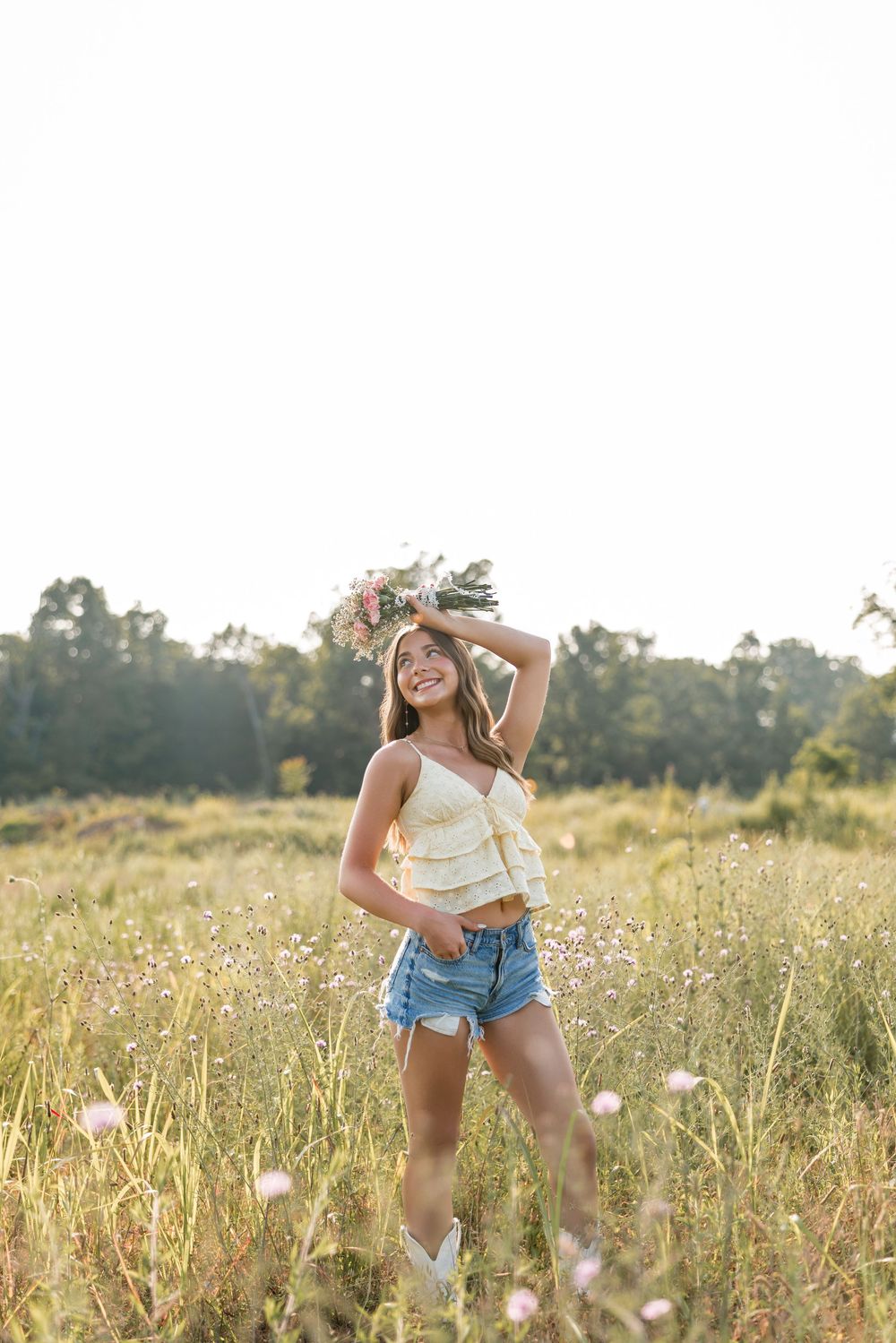 Sunny meadow filled with wildflowers and tall grass during golden hour creating a dreamy summer landscape.