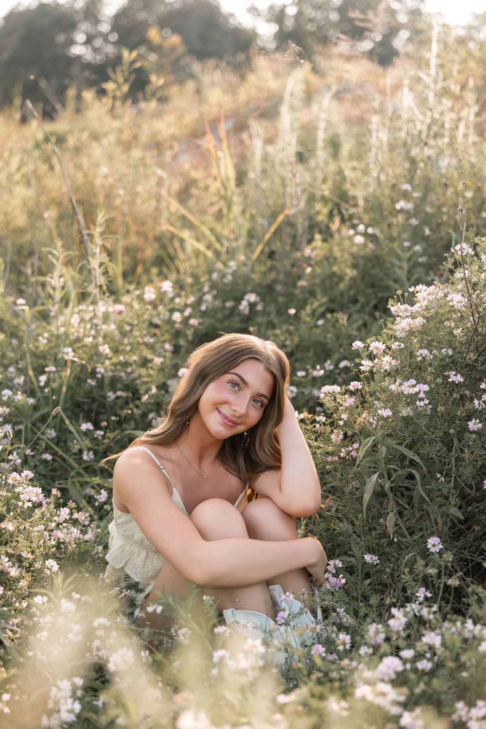 Ethereal outdoor portrait in a dreamy wildflower meadow at golden hour with soft natural lighting and delicate daisies.