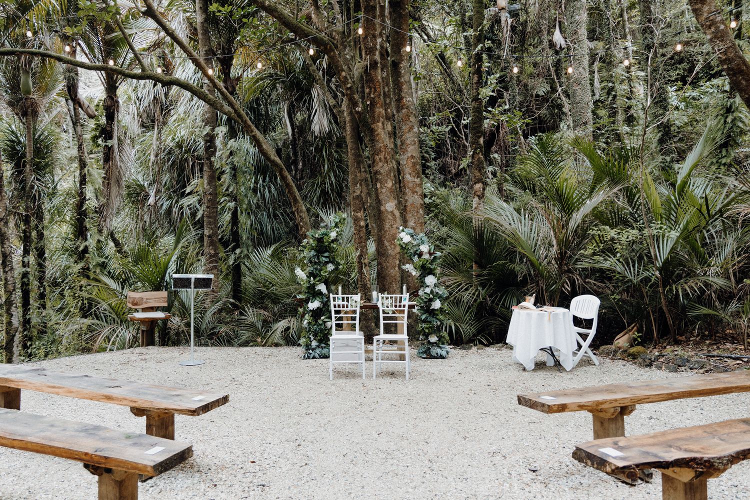 Intimate outdoor wedding ceremony setup with wooden benches captured by Apertured Media Auckland Wedding Photographer.