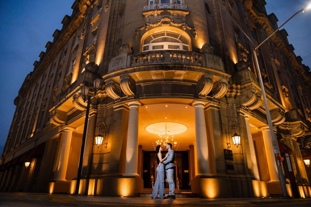 A nighttime wedding portrait in front of an elegantly lit historic building.