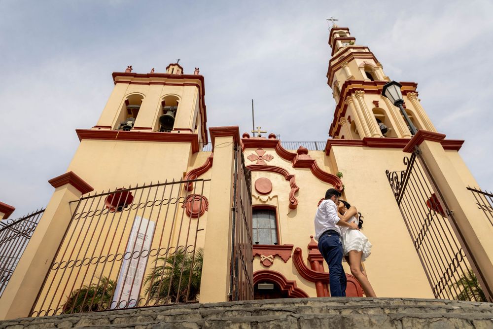 A Spanish colonial church with twin towers serves as backdrop for a romantic moment on stone steps.