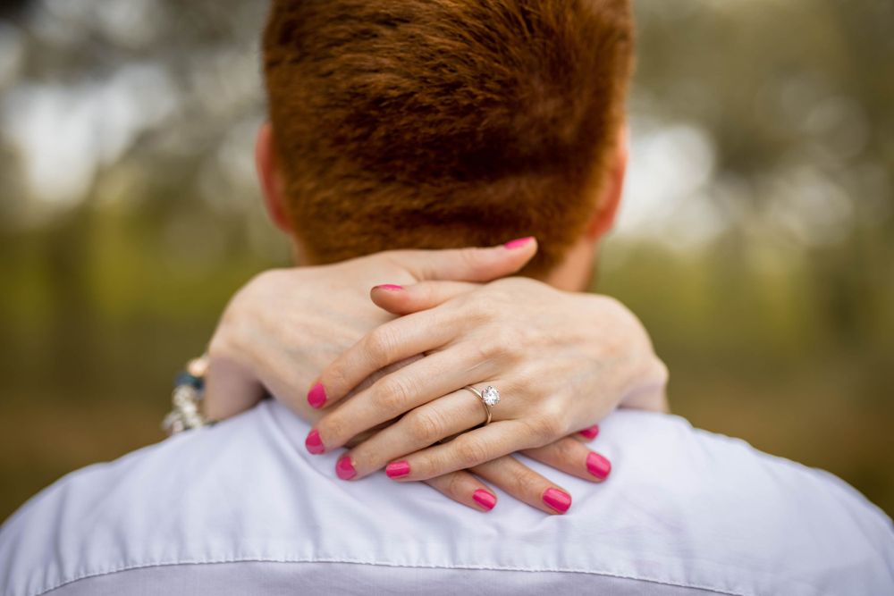 Close-up of pink painted fingernails clasped around a neck showing intimacy and connection.