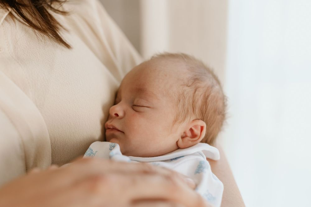 A peaceful sleeping newborn baby wearing a light blue outfit.