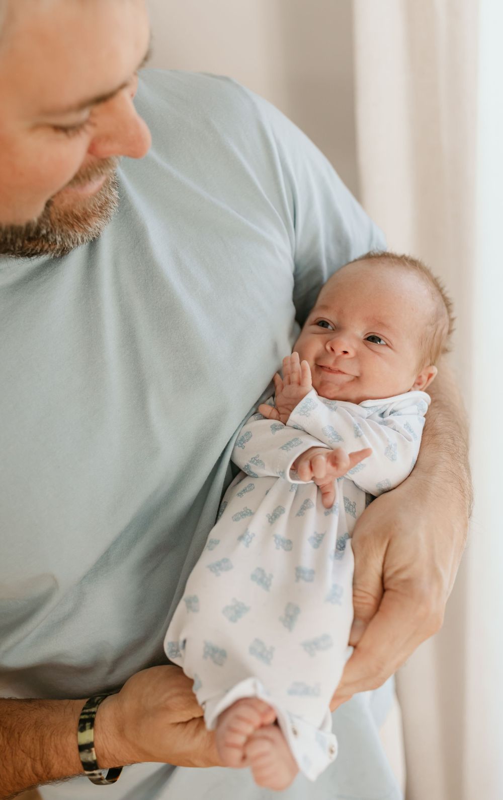 A tender moment with a smiling baby in a patterned onesie.