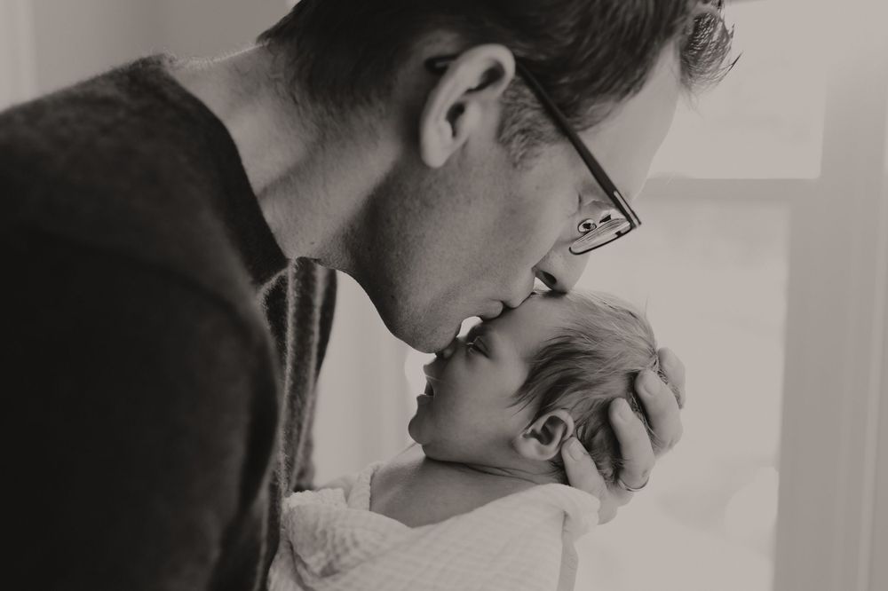 A tender black and white photo showing a gentle moment with a newborn baby.