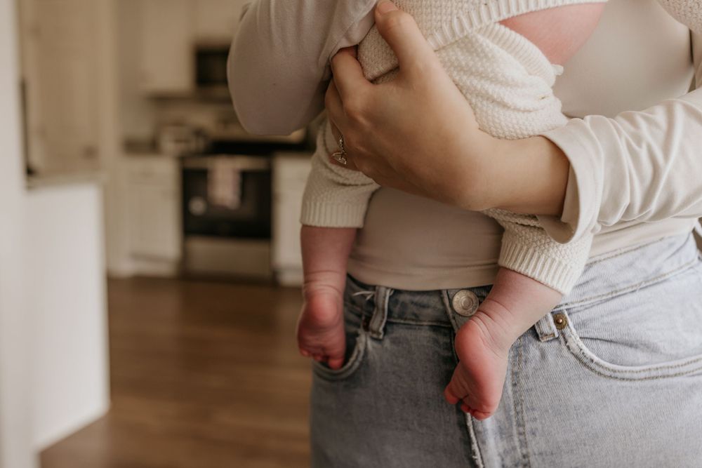 Close-up view of parent holding infant's feet in casual home setting.