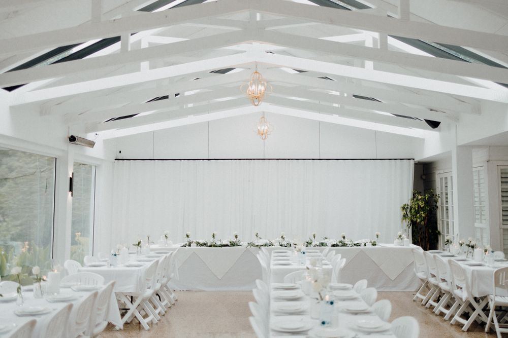 White wedding reception venue with vaulted ceiling beams captured by Apertured Media Auckland Wedding Photographer