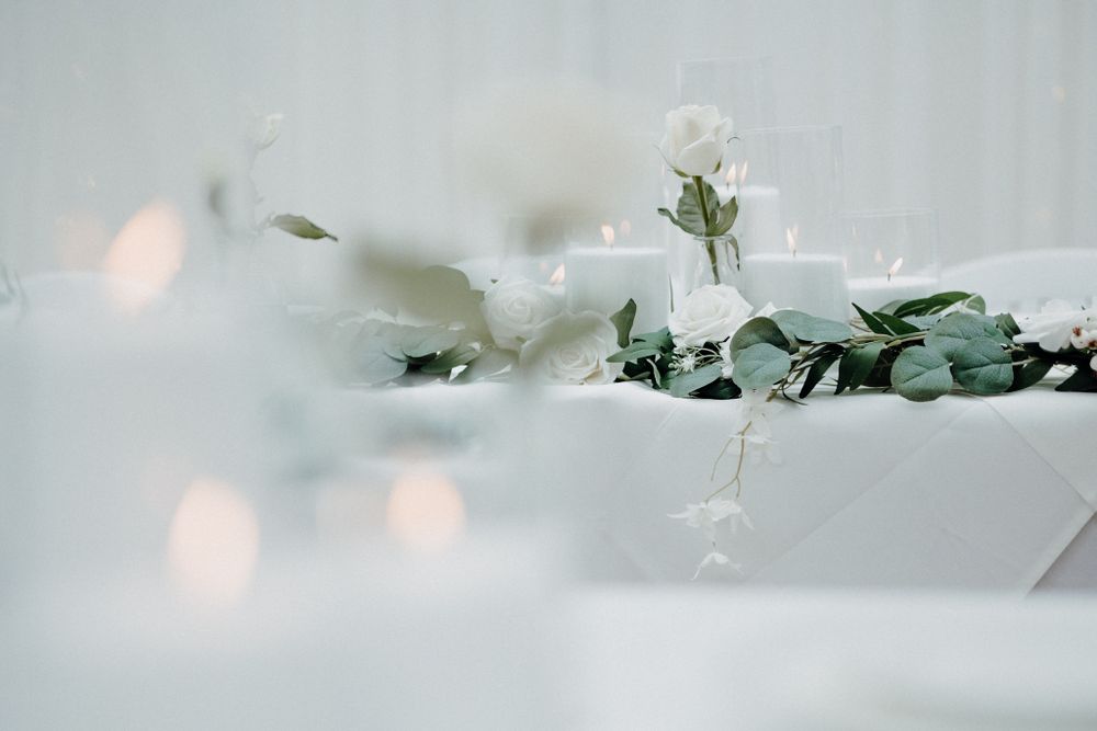 White flowers and greenery arranged on a white surface captured by Apertured Media Auckland Wedding Photographer.