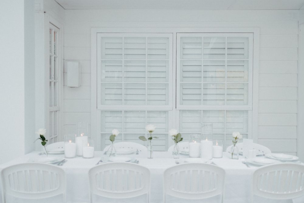 Elegant white dining room setup with plantation shutters captured by Apertured Media Auckland Wedding Photographer.