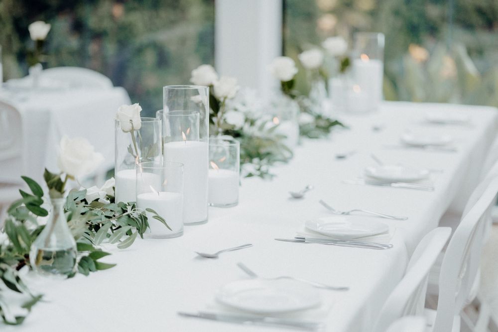 Elegant white wedding reception table setting with fresh greenery garland captured by Apertured Media Auckland Wedding Photographer.